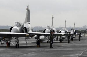 Aviones de combate en una base militar con personal militar de pie.
