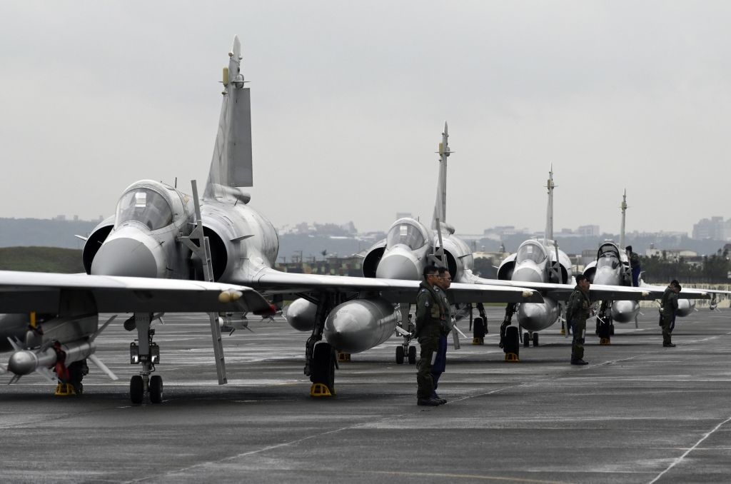 Aviones de combate en una base militar con personal militar de pie.