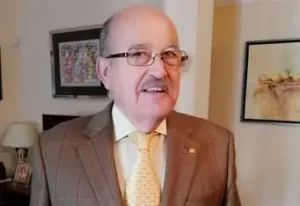 Hombre mayor con gafas y traje en un entorno doméstico