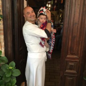Niño vestido de indio con camiseta del Atlético de Madrid en brazos de su padre.