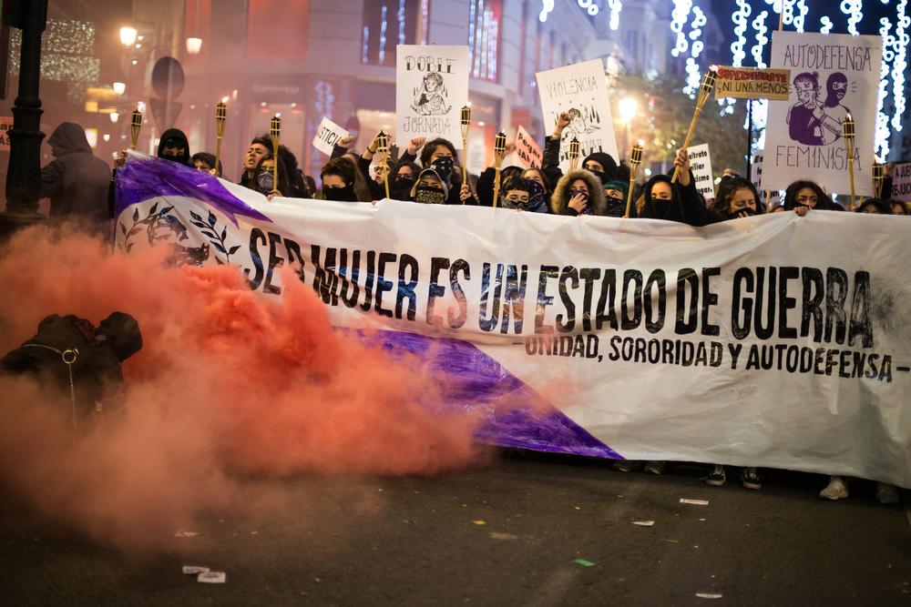 Manifestación feminista con pancarta y humo de colores en la noche