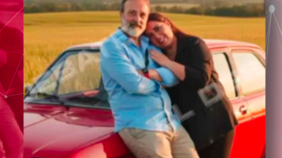 Pareja posando junto a un coche rojo en un campo