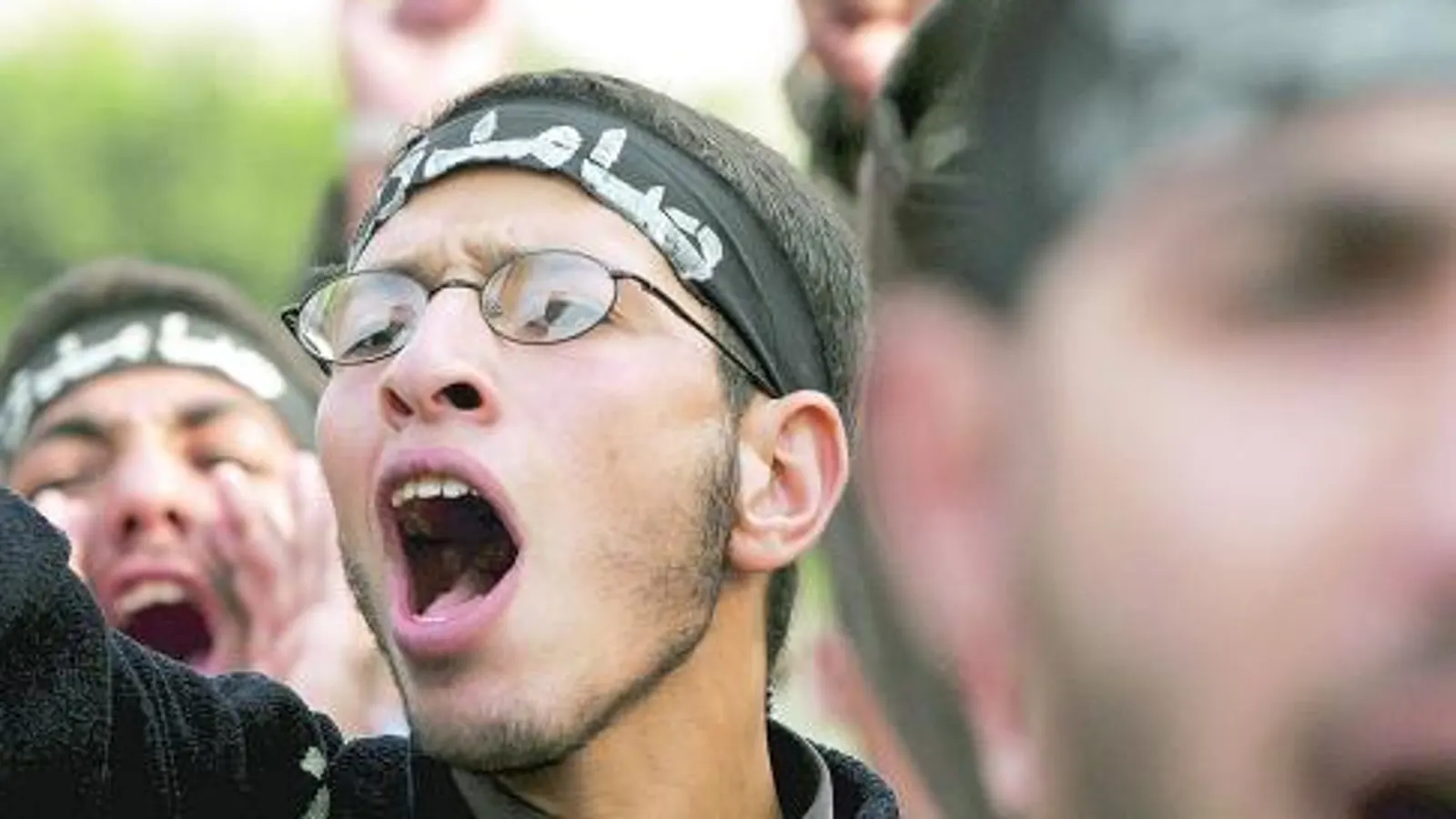 Joven con bandana gritando en una manifestación sobre inmigración islámica