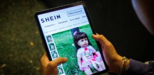 Persona sosteniendo una tablet mostrando muñeca infantil en sitio web de Shein