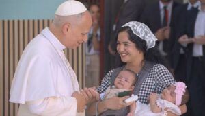 El Papa León XIV interactuando con una mujer y sus gemelos en un centro de atención