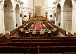Interior del Parlamento andaluz con asientos vacíos y decoración