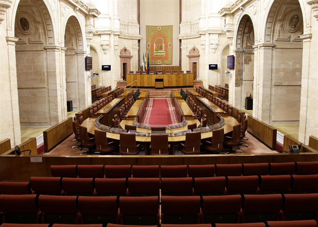 Interior del Parlamento andaluz con asientos vacíos y decoración
