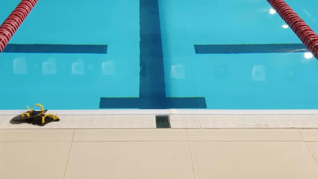 Vista de una piscina municipal con agua azul y flotadores