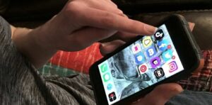 Persona usando un teléfono móvil con aplicaciones de redes sociales visibles