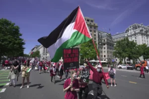 Manifestantes sosteniendo pancartas y una bandera palestina en una protesta.