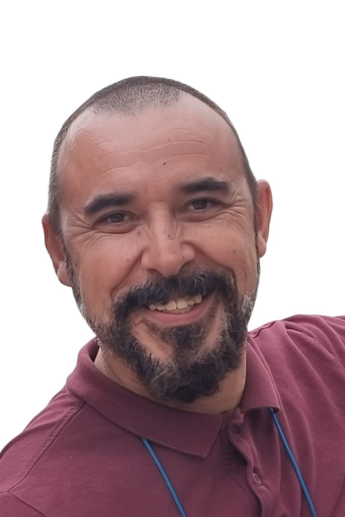 Retrato de un hombre sonriendo con barba y camiseta de color burdeos