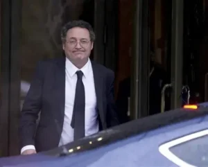 Hombre saliendo de un edificio, vestido de traje y corbata.